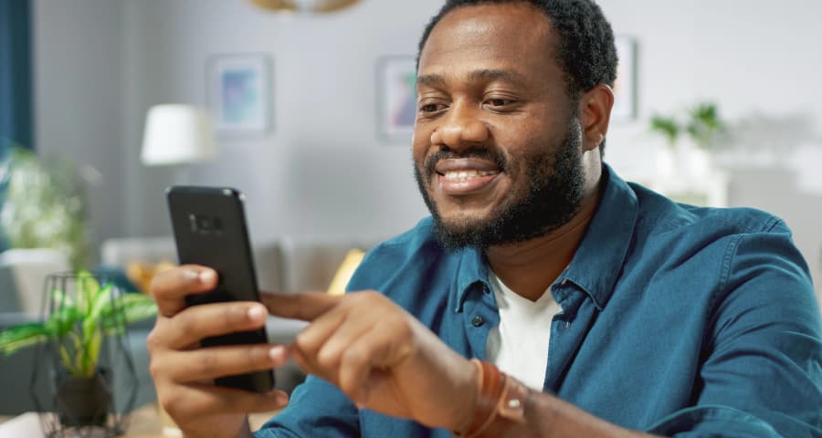 Man at home interacting with a home security app on his cell phone